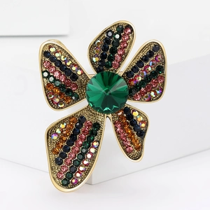 Close-up of elegant flower brooch with colorful rhinestones and central green crystal