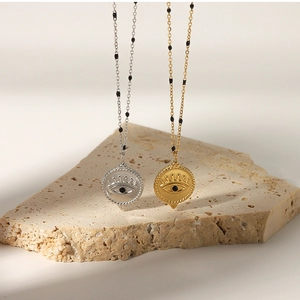 Detail view of gold and silver evil eye pendant necklaces draped over a stone pedestal