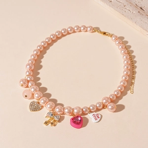 Détail du ras-du-cou en perles roses avec noeud, coeur strass et breloque HUG ME
