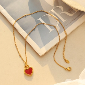 Collier plaqué or 18 carats avec pendentif coeur rouge double face sur un magazine