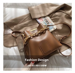 Detail view of brown bucket bag with gold chain strap and matte leather texture