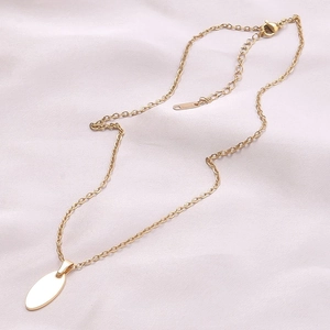 Detailed view of gold oval pendant on thin chain over elegant pink silk fabric background