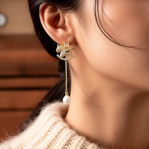 Detail of 18k gold plated rocking horse earring with cubic zirconia and pearl tassel