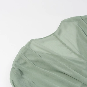 Detail of the V-neckline stitching and ruched texture on the green chiffon dress