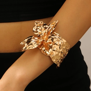 Makro-Detail des goldenen Manschettenarmbands mit unregelmäßiger gefalteter Blumenstruktur
