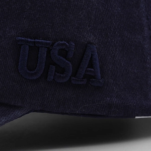 Macro shot of 3D embroidered USA logo on a navy blue cotton baseball cap detail