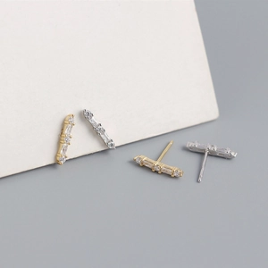 Detailed close-up of gold and silver bar earrings with rectangular crystal stones