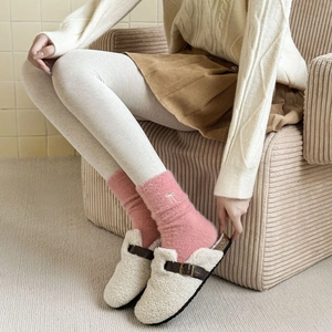 Pink plush socks with white bows shown with fluffy slippers for a cozy winter look