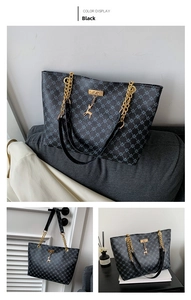 Dettaglio borsa shopper nera con trama geometrica, catena dorata e ciondolo cervo