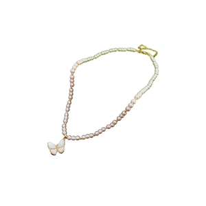 Collier papillon plaqué or avec perles blanches et zircon sur un fond blanc pur