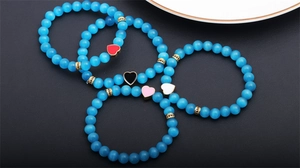 Blue cat eye stone beaded bracelets with colorful heart charms on a black textured surface