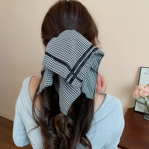 Close-up of black and white houndstooth checkered bow hair tie on a ponytail
