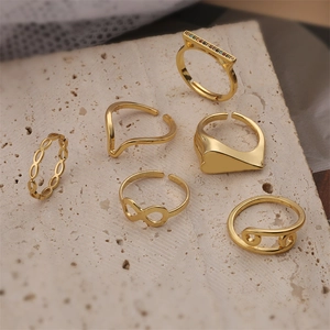 Vista detallada de seis anillos dorados con motivos de infinito y geometría de alfiler