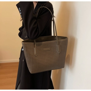Detail of taupe woven leather tote bag texture and long handles shown on model