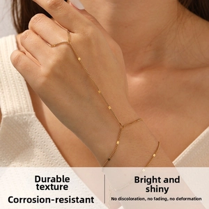 Detail of a minimalist gold hand chain with delicate links and square metal charms