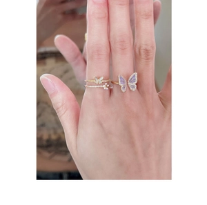 Detail of hand wearing a purple butterfly ring and a gold double-layer floral ring