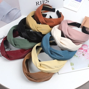 Extra wide criss-cross soft faux leather headbands in assorted colors displayed on a desk