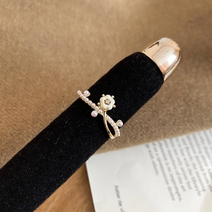 Détail d'une bague fleur plaquée or 14k avec nacre et perles sur support d'exposition