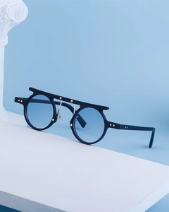 Detail of round punk sunglasses with blue lenses and gold star rivets on blue background