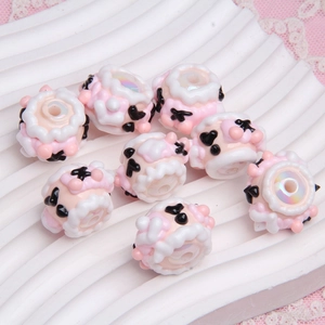 Macro shot of handmade sheep-shaped pink and white resin beads for DIY jewelry crafts