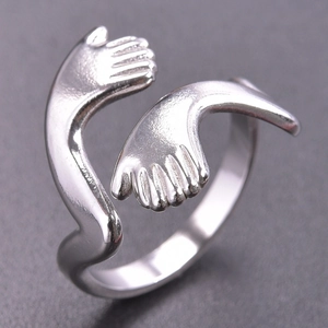 Macro shot of silver hug hands open ring in polished stainless steel with fine details