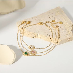 Detail of vintage gold bracelets with emerald, pink, and clear oval zircon pendants