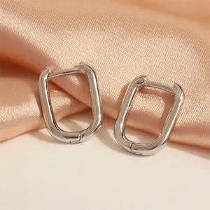 Detailed shot of silver U-shaped geometric hoop earrings on champagne silk fabric
