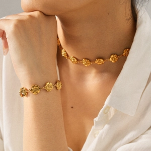 Détail de l'ensemble collier et bracelet rose en or 18k sur une chemise blanche
