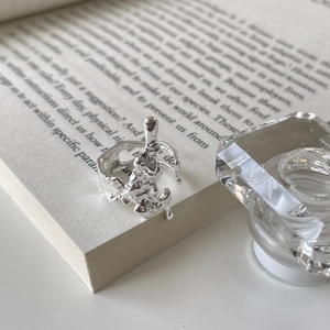 Detailed close-up of molten silver irregular textured ring on a book background
