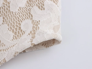 Detailed macro view of white floral hollow lace fabric with light beige inner lining
