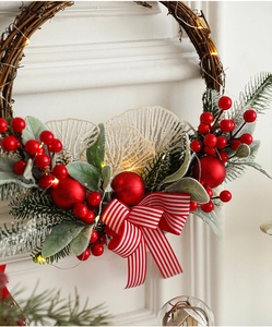 Detail of Christmas wreath with red berries, pine needles, and warm LED lights