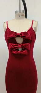 Détail de robe de soirée en velours rouge avec trois nœuds étagés sur le bustier