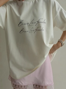 Detail of white cotton tee with Brave Love Freedom print and lace satin skirt