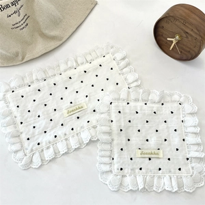 Detail of white cotton linen placemats with black heart patterns and lace borders