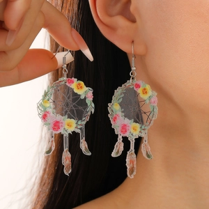Détail de boucles d'oreilles attrape-rêves bohèmes avec fleurs sur acrylique clair