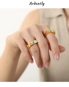 Close-up of gold-plated rings featuring inset pink square, blue heart, and white round stones
