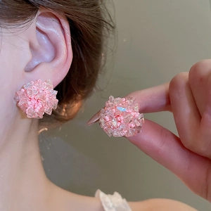 Détail des boucles d'oreilles boules en perles de cristal rose portées avec style floral