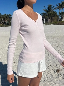 Close-up of light pink ribbed V-neck long sleeve tee with button placket detail