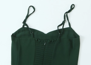 Detail of dark green dress back featuring smocked elastic fabric and adjustable straps