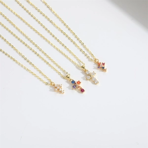 Detailed macro view of four golden cross pendant necklaces with white and colorful zircon gems