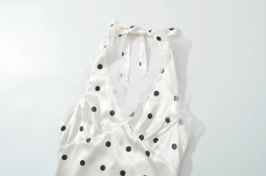 Detailed flat lay of cream polka dot halter top with lace trim and silk texture