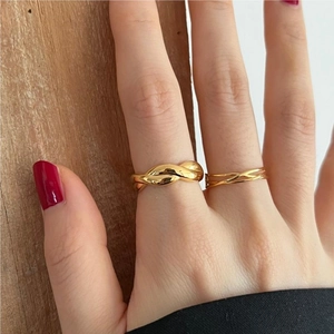 Detail of twisted and multi-layer gold rings on model hand with red nails