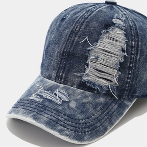 Distressed vintage navy denim baseball cap with frayed ripped details and washed texture