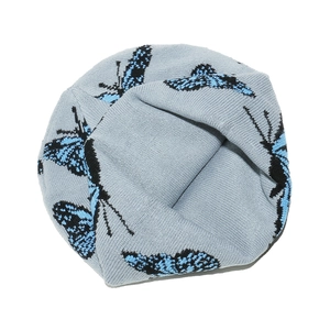 Détail du bonnet en tricot bleu clair avec motif papillon jacquard noir et texture
