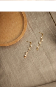Close-up of golden wheat tassel earrings featuring natural freshwater pearls and chains