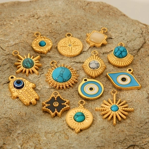 Golden Hamsa Hand and Evil Eye charms with turquoise inlay on a natural rock surface