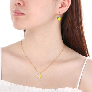 Gros plan d'un collier et de boucles d'oreilles dorés avec citrons jaunes sur un mannequin