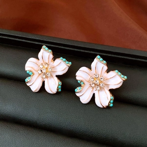 Detail of vintage flower earrings with white petals, gold trim and turquoise beads