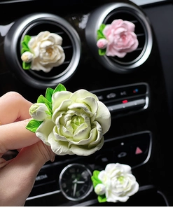 Close-up of white and pink jasmine flower car aroma diffusers on air vent outlet
