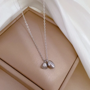Macro detail of a silver lotus seed and heart pendant necklace on white silk fabric
